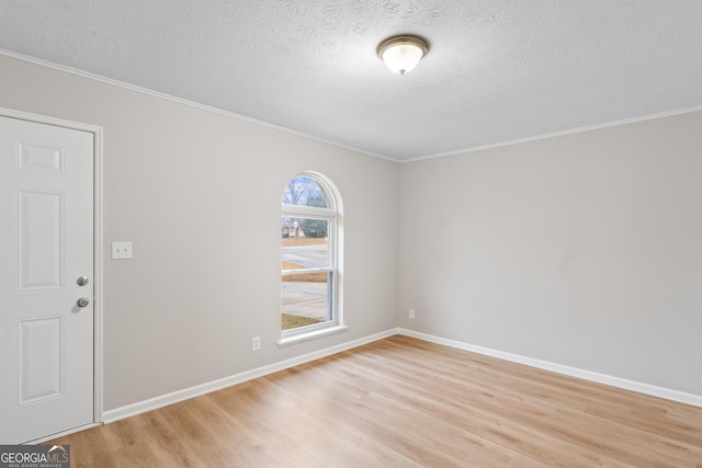 spare room featuring light wood-style floors, baseboards, and a textured ceiling