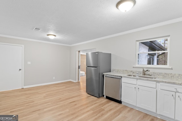 kitchen with light wood finished floors, stainless steel appliances, visible vents, white cabinetry, and a sink