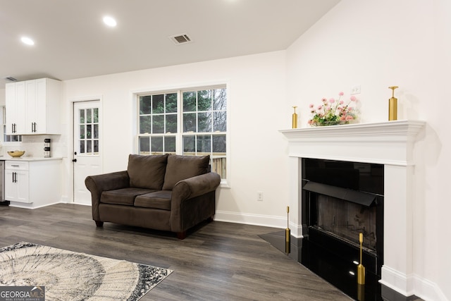 living room with dark wood-type flooring and a healthy amount of sunlight