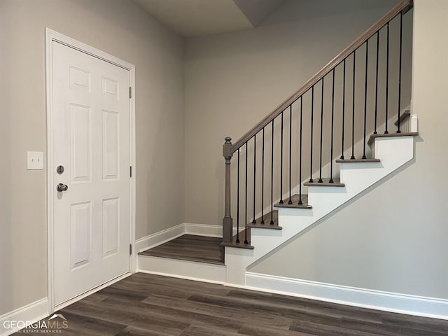 foyer entrance with stairs, wood finished floors, and baseboards