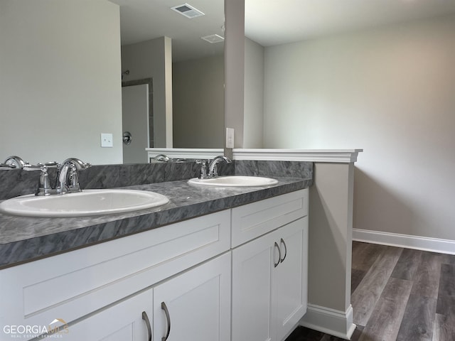 bathroom with double vanity, visible vents, a sink, and wood finished floors