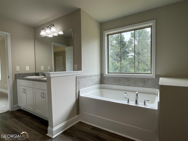 full bathroom with a bath, wood finished floors, vanity, and baseboards