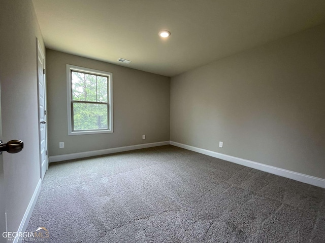 unfurnished room featuring carpet, visible vents, and baseboards