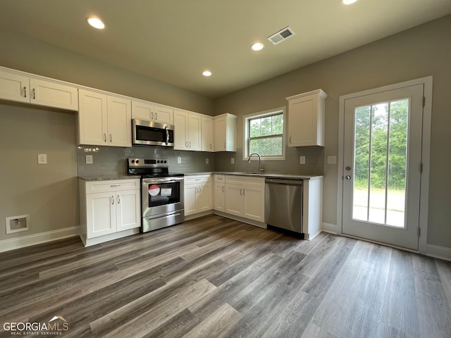 kitchen with visible vents, decorative backsplash, appliances with stainless steel finishes, white cabinetry, and a sink