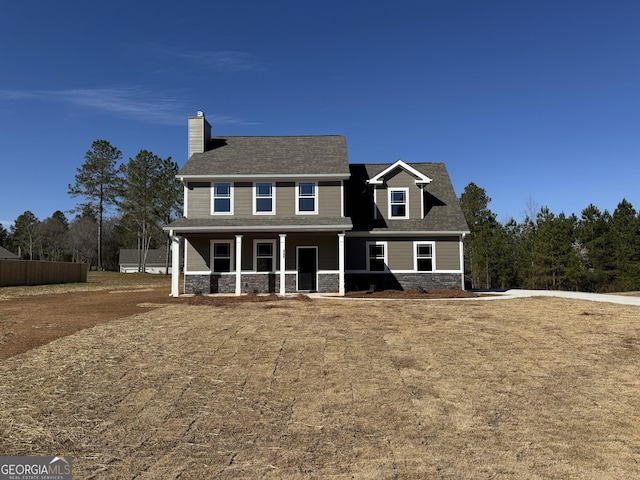 view of front facade with stone siding, a chimney, and a porch