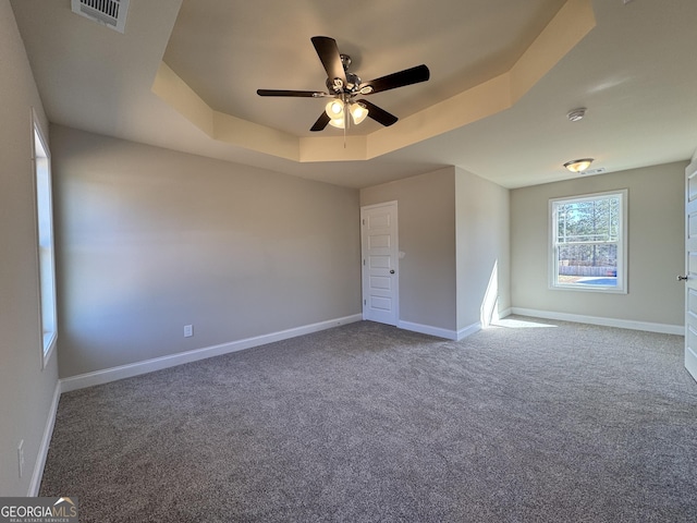 unfurnished bedroom with carpet floors, a raised ceiling, visible vents, ceiling fan, and baseboards