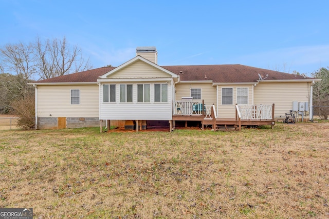 rear view of house featuring a deck, a lawn, a chimney, and fence