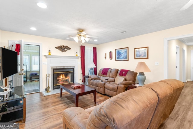 living area featuring a fireplace with flush hearth, recessed lighting, ceiling fan, and light wood finished floors