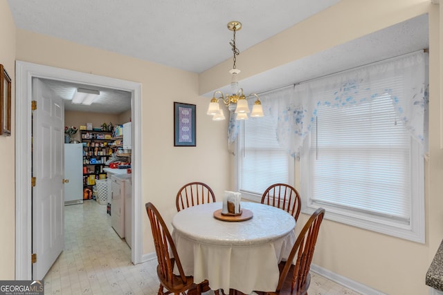 dining room with a chandelier, washing machine and dryer, baseboards, and light floors