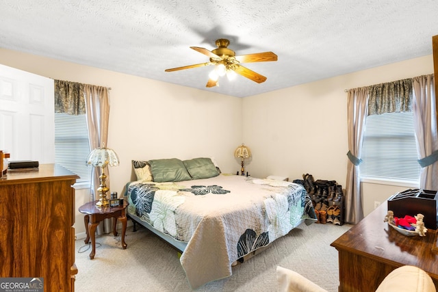 carpeted bedroom with ceiling fan, multiple windows, and a textured ceiling