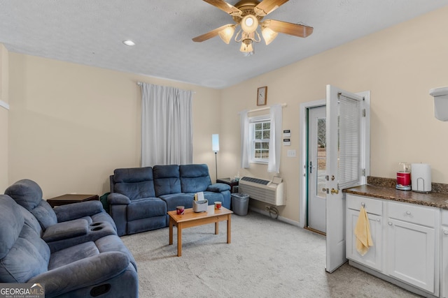 living room with ceiling fan, a textured ceiling, baseboards, and light colored carpet