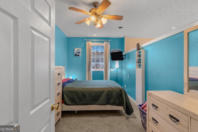 carpeted bedroom featuring a ceiling fan, visible vents, and a textured ceiling