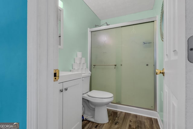 bathroom featuring a textured ceiling, a stall shower, wood finished floors, and toilet