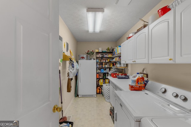 laundry area with a textured ceiling, light floors, washer and clothes dryer, and cabinet space