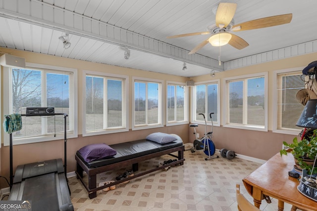 workout room featuring ceiling fan, plenty of natural light, rail lighting, and baseboards