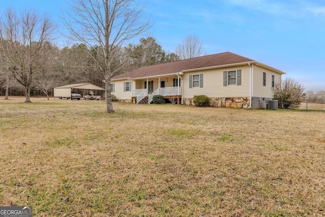 ranch-style home featuring covered porch, central AC unit, a front lawn, and a detached carport