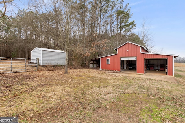 view of pole building with driveway and fence