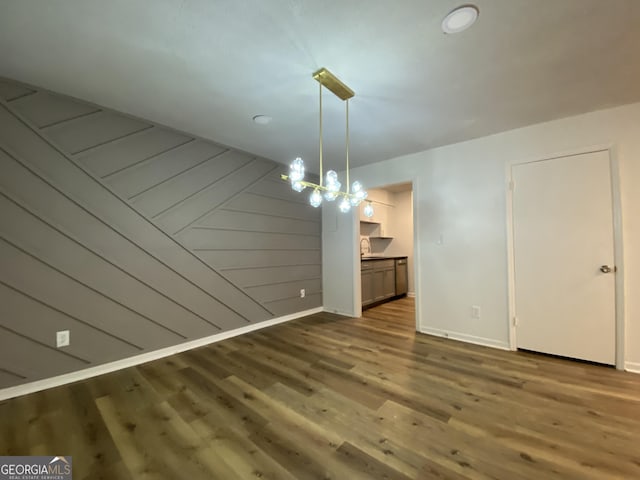 unfurnished dining area featuring hardwood / wood-style floors, a notable chandelier, and wood walls