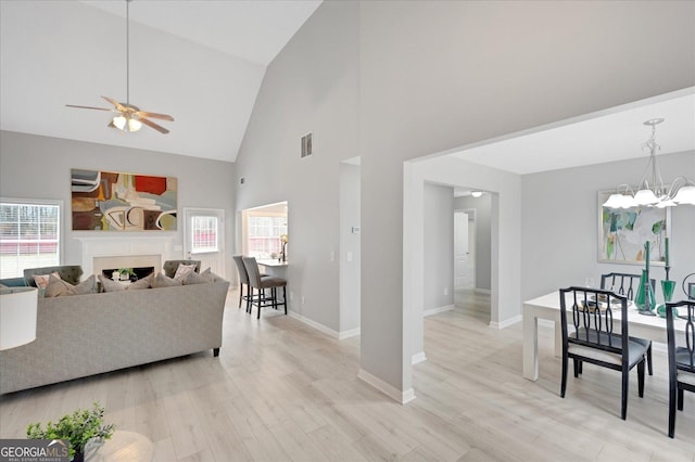 living room with a wall unit AC, ceiling fan with notable chandelier, light hardwood / wood-style flooring, and a wealth of natural light