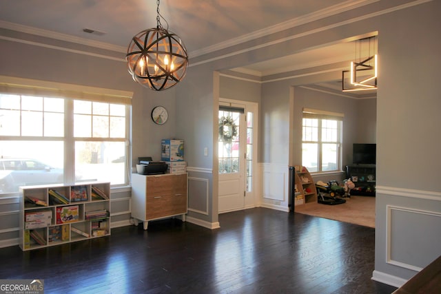 entryway with dark wood-type flooring, ornamental molding, and a chandelier