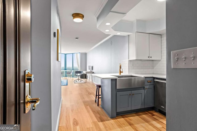 kitchen with sink, dishwasher, ornamental molding, a kitchen bar, and kitchen peninsula