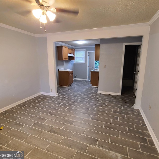 unfurnished living room featuring ceiling fan, ornamental molding, and a textured ceiling