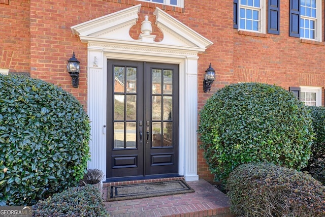 view of exterior entry featuring french doors and brick siding