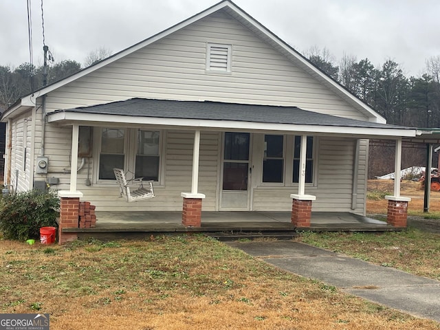 bungalow featuring a porch and a front lawn