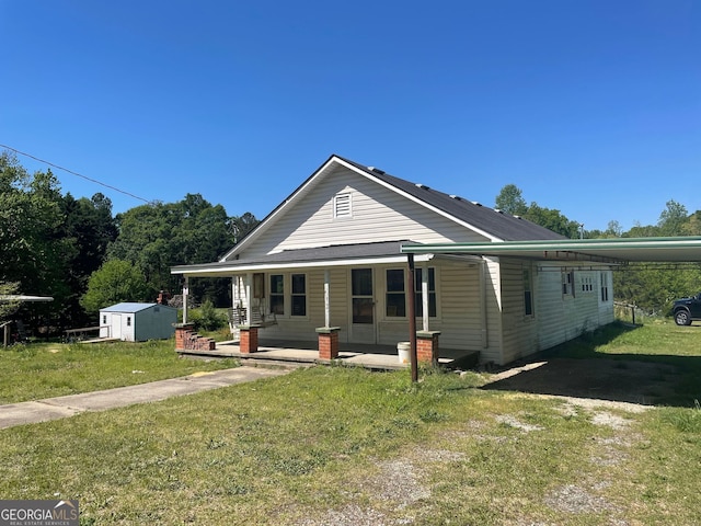 view of front of house with a carport, a front yard, a storage unit, and covered porch