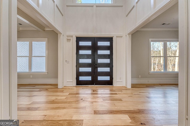 entrance foyer with a towering ceiling, light hardwood / wood-style flooring, and french doors