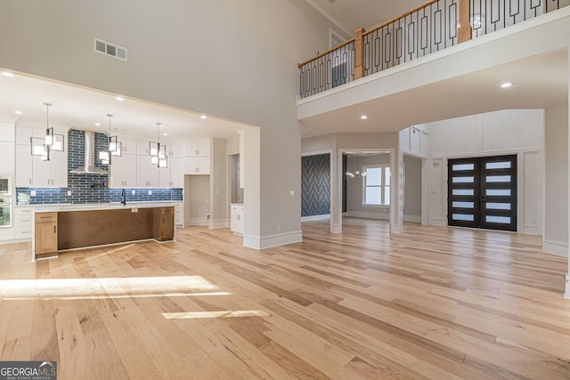 unfurnished living room featuring a high ceiling, sink, and light hardwood / wood-style floors