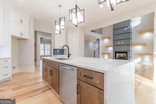 kitchen featuring sink, white cabinetry, light stone counters, an island with sink, and light hardwood / wood-style floors