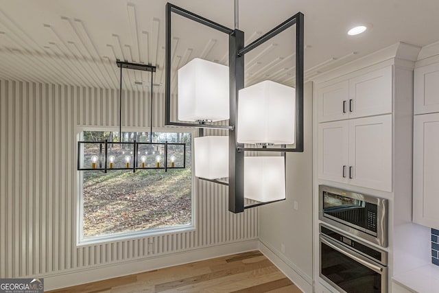 kitchen with stainless steel appliances, white cabinets, and light wood-type flooring