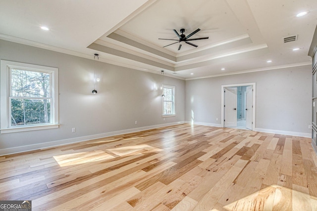 spare room with crown molding, a tray ceiling, ceiling fan, and light wood-type flooring