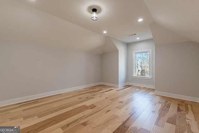 additional living space featuring vaulted ceiling and light hardwood / wood-style floors