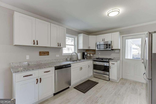 kitchen with sink, white cabinetry, light hardwood / wood-style flooring, appliances with stainless steel finishes, and light stone countertops