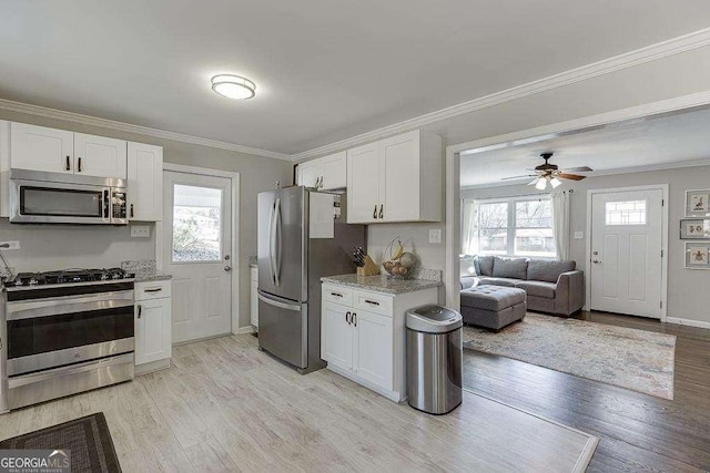 kitchen with crown molding, light stone counters, appliances with stainless steel finishes, light hardwood / wood-style floors, and white cabinets