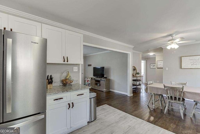 kitchen featuring hardwood / wood-style flooring, stainless steel fridge, crown molding, and white cabinets