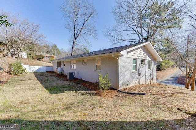 view of side of home featuring central AC unit and a lawn