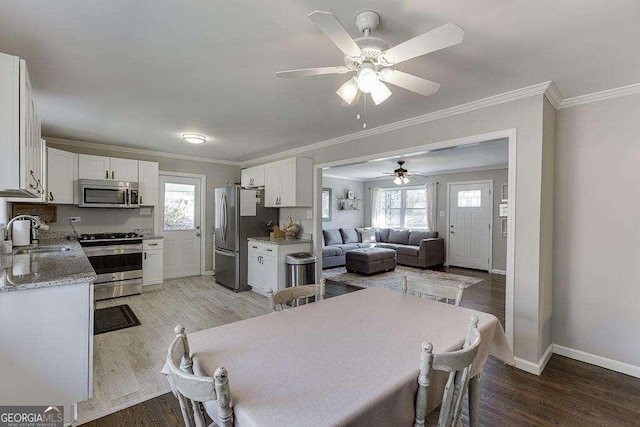 dining space featuring sink, plenty of natural light, ornamental molding, and light wood-type flooring