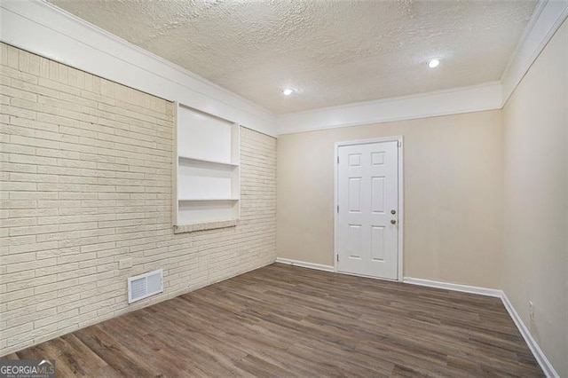 1146 Canal St, Decatur, GA 30032 - empty room featuring crown molding, dark wood-type flooring, built in features, a textured ceiling, and brick wall