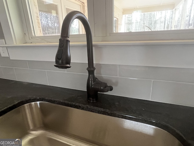 interior details with tasteful backsplash, sink, and dark stone countertops