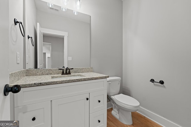 bathroom with hardwood / wood-style flooring, vanity, and toilet