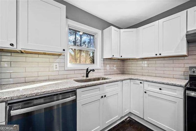 kitchen with appliances with stainless steel finishes, white cabinetry, sink, backsplash, and light stone countertops