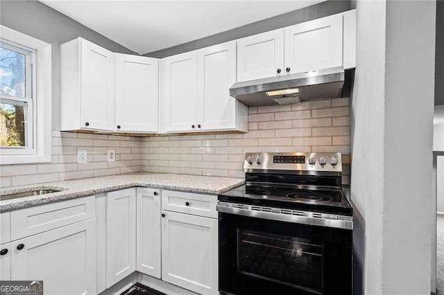 kitchen with decorative backsplash, white cabinets, light stone counters, and stainless steel range with electric stovetop