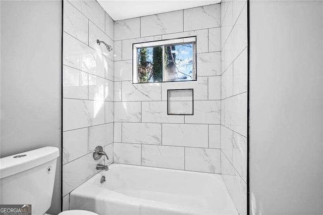 bathroom with tiled shower / bath combo and toilet