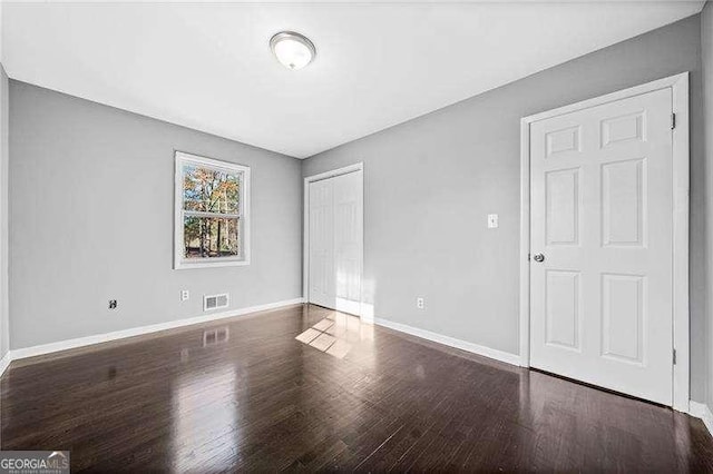 unfurnished bedroom with dark hardwood / wood-style floors and a closet