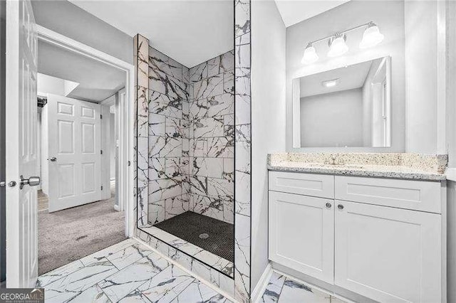 bathroom with a tile shower and vanity