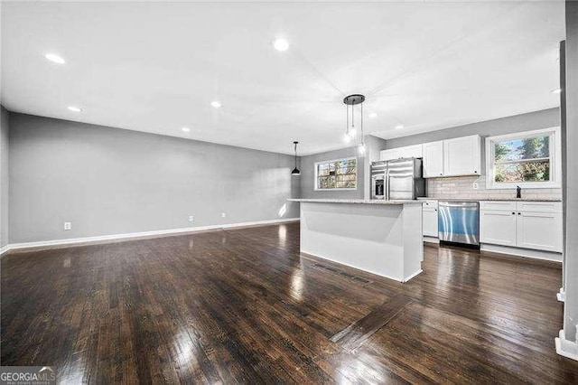 kitchen featuring appliances with stainless steel finishes, white cabinets, dark hardwood / wood-style flooring, hanging light fixtures, and a center island