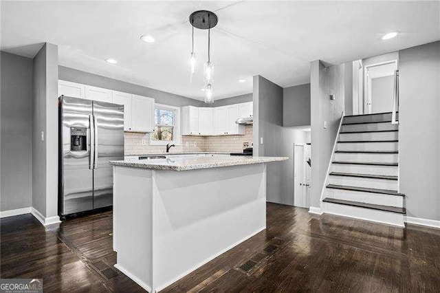 kitchen with white cabinetry, stainless steel refrigerator with ice dispenser, a kitchen island, dark hardwood / wood-style flooring, and decorative light fixtures